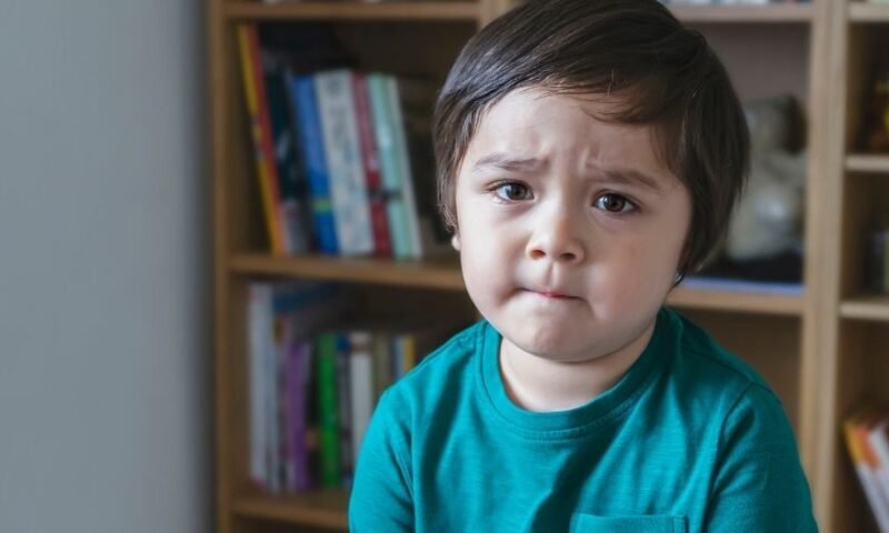 criança na biblioteca com feição triste - filho a lidar com as emoções