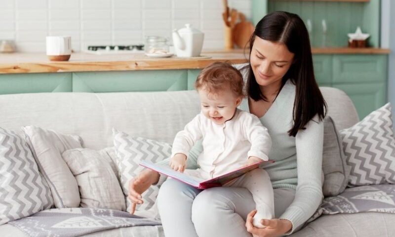 Mãe lendo um livro com seu bebê no colo - exemplo dos pais é fundamental na Educação Infantil